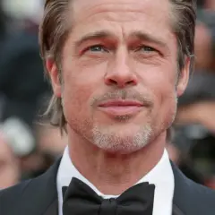 Brad Pitt w garniturze i muszce, gwiazda wielu filmów, z siwiejącą brodą i zmarszczkami wokół oczu.