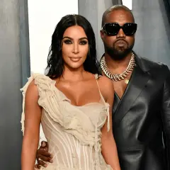 Kim Kardashian i jej mąż, Kanye West, pozują do zdjęć w eleganckich strojach.