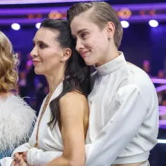 Katarzyna Zillmann i jej partnerka w białych strojach, czule objęte, na tle fioletowych świateł.