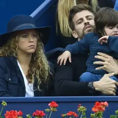 Shakira i Pique oglądają mecz, siedząc obok siebie. Pique trzyma na rękach dziecko.