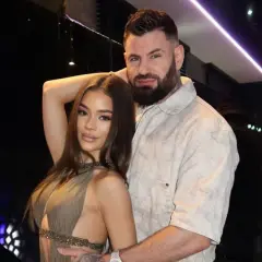 Wojtek Gola z dziewczyną, w eleganckich strojach, pozują do zdjęcia w stylowym wnętrzu.