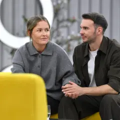 Olga Frycz i jej partner, Tomasz Kwaśniewski, siedzą obok siebie na kanapie, trzymając się za ręce.