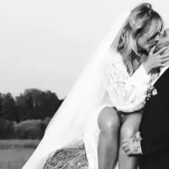 Patrycja Markowska i jej mąż w czułym uścisku na tle wiejskiego krajobrazu.
