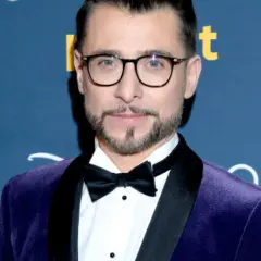 Kacper Kuszewski w fioletowym aksamitnym garniturze z czarną muszką. Wygląda elegancko, jakby wybierał się na galę z żoną.