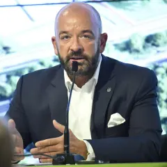 Jacek Sutryk z partnerem podczas konferencji prasowej. Mężczyzna w garniturze przemawia do mikrofonu.