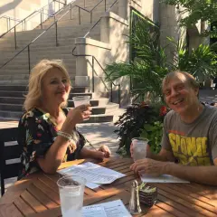 Tom Logan, mąż Majki Jeżowskiej, uśmiecha się do aparatu, siedząc przy stoliku na zewnątrz z żoną.