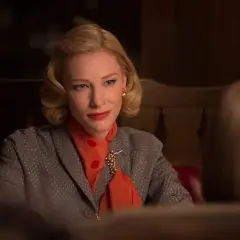 Cate Blanchett w eleganckiej stylizacji, z rudym szalem i broszką, w scenie z jednego ze swoich filmów.