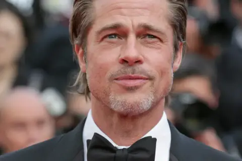 Brad Pitt w garniturze i muszce, gwiazda wielu filmów, z siwiejącą brodą i zmarszczkami wokół oczu.