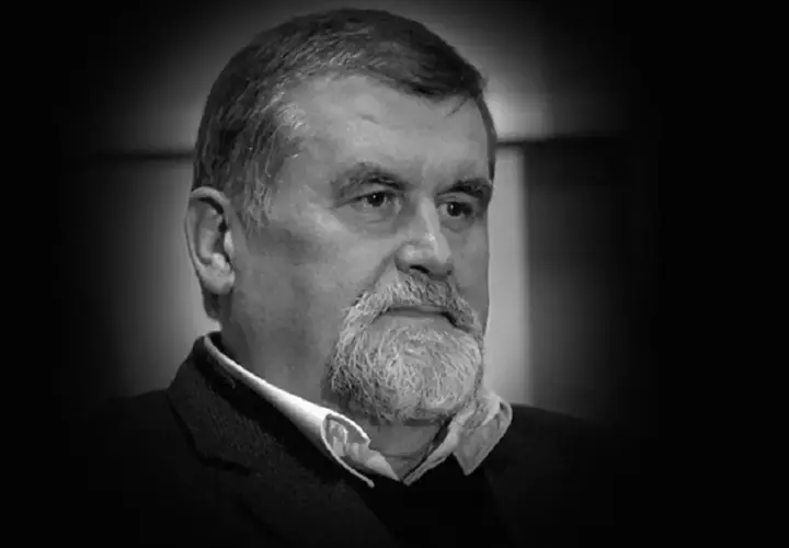 Portret Andrzeja Zielińskiego, mężczyzny z siwą brodą i zmarszczkami, w czarnym garniturze.