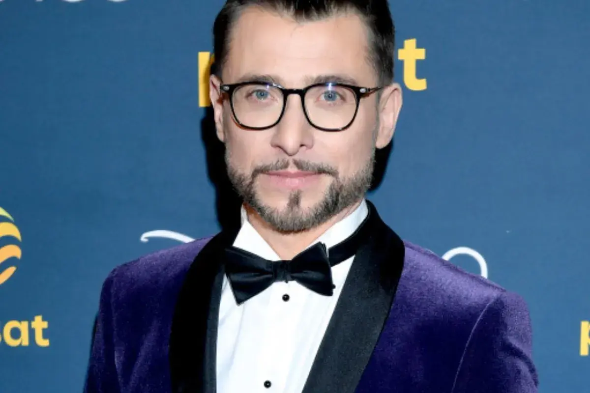 Kacper Kuszewski w fioletowym aksamitnym garniturze z czarną muszką. Wygląda elegancko, jakby wybierał się na galę z żoną.