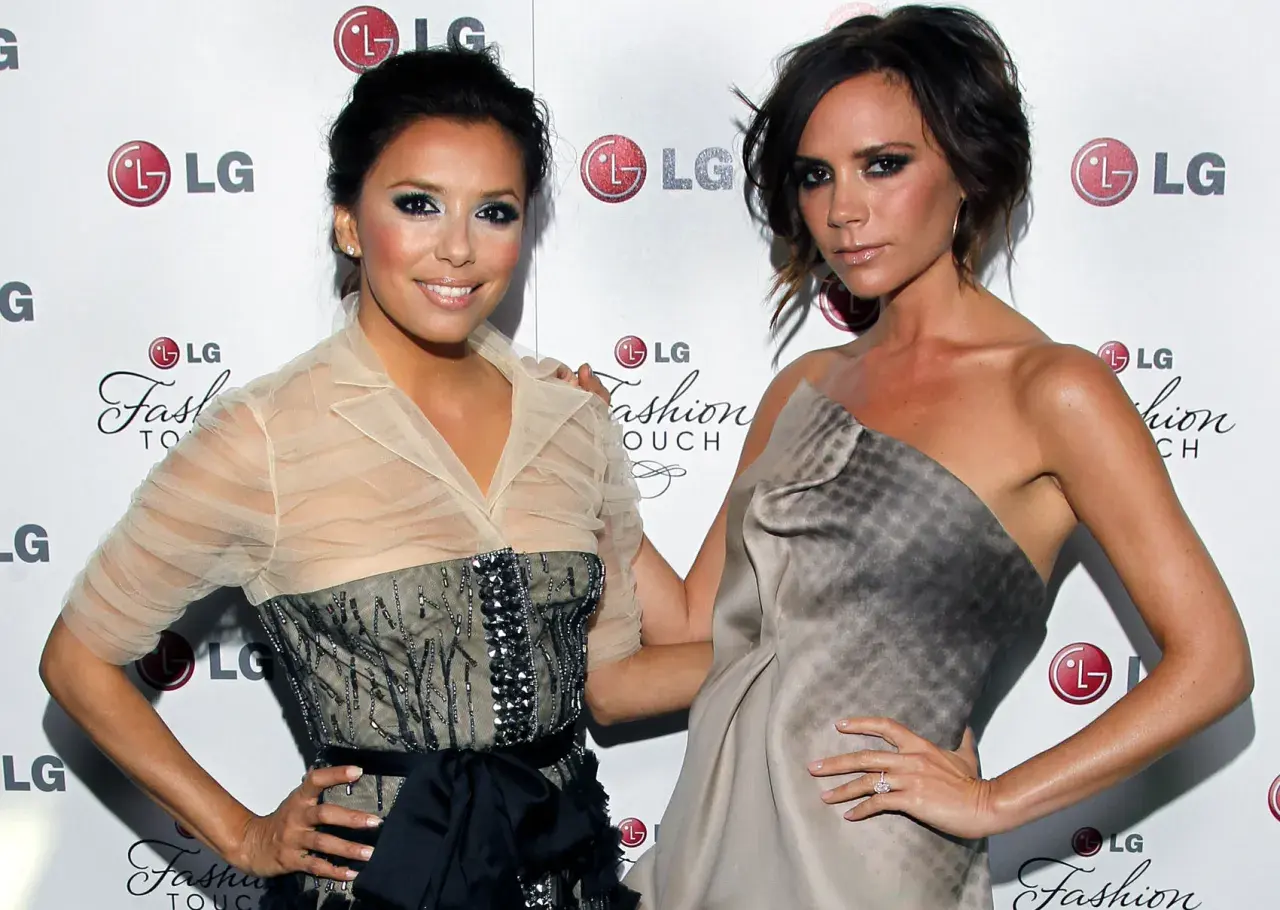 Eva Longoria i Victoria Beckham pozują do zdjęć, obie w eleganckich kreacjach. Ich uśmiechy i gesty sugerują radosne wags.