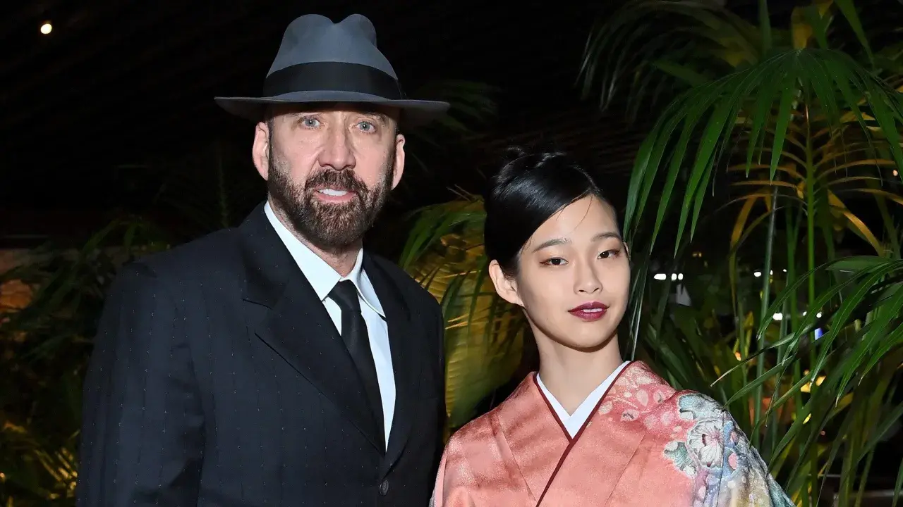 Nicolas Cage w kapeluszu i garniturze obok swojej żony w kimonie.