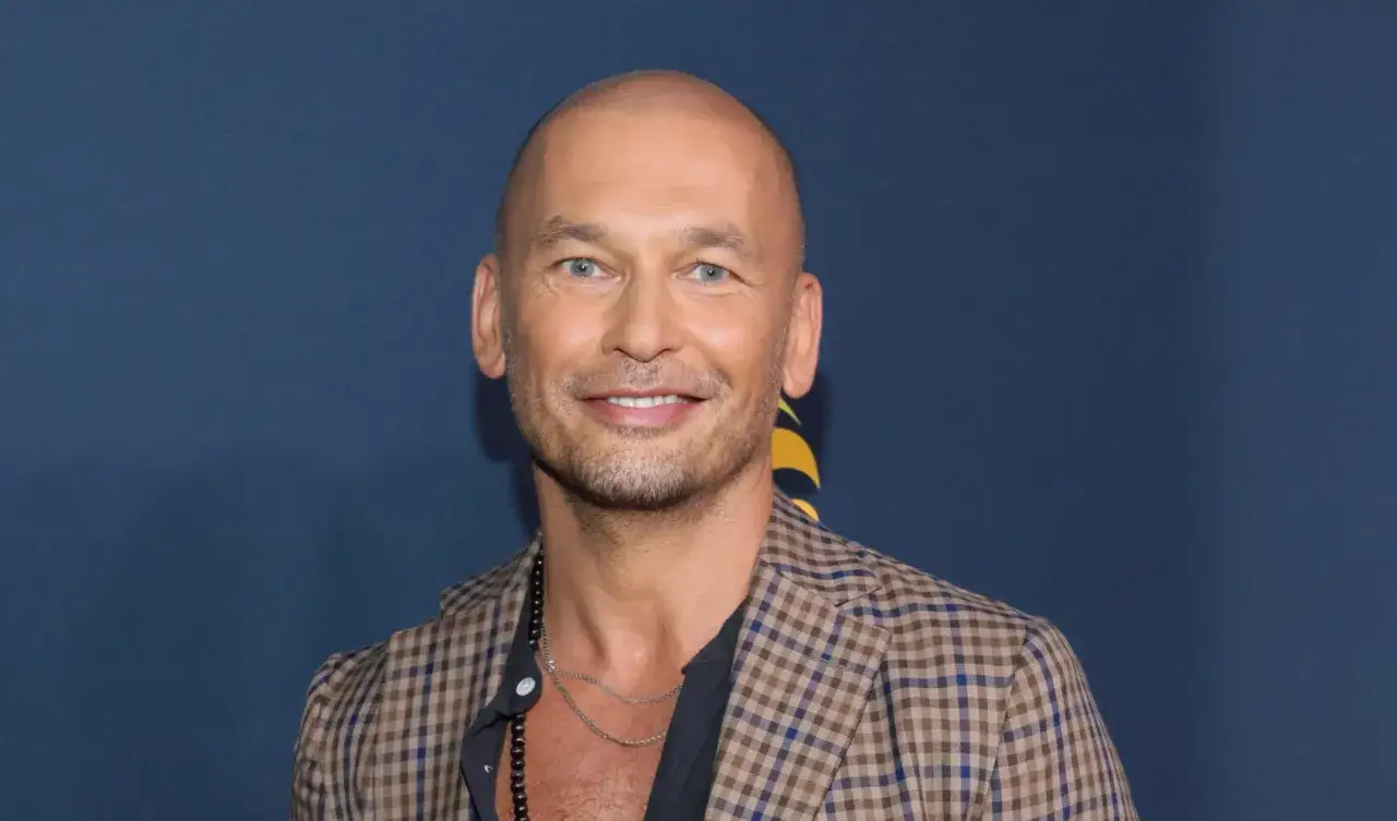 Tomasz Wygoda, z żoną i dziećmi, uśmiecha się do zdjęcia w kratkę.