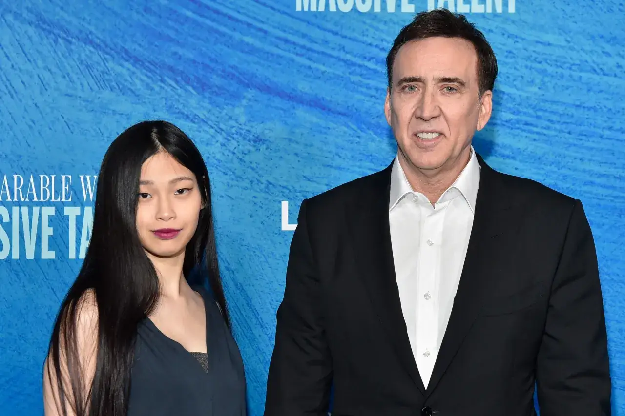 Nicolas Cage z żoną na tle niebieskiego materiału z napisem