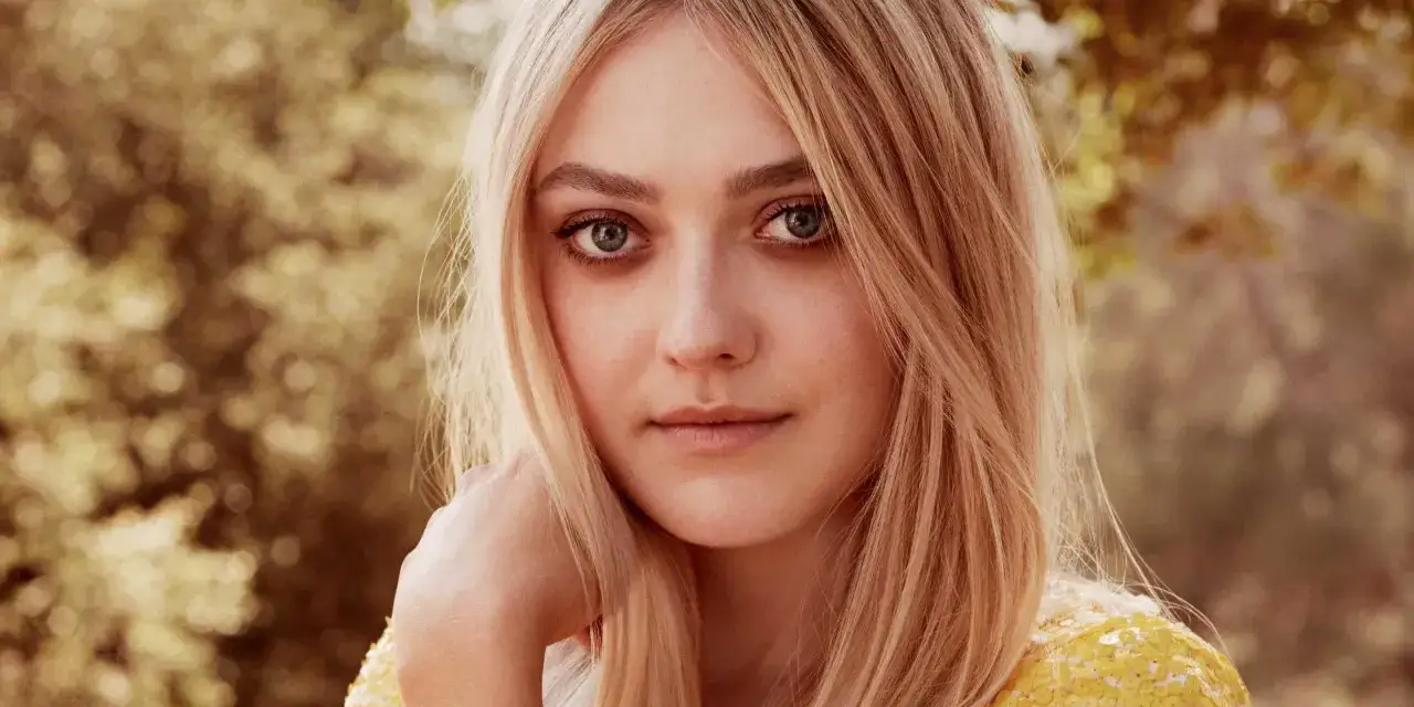 Dakota Fanning, znana z filmów, seriali i programów, z blond włosami i niebieskimi oczami, spogląda wprost.