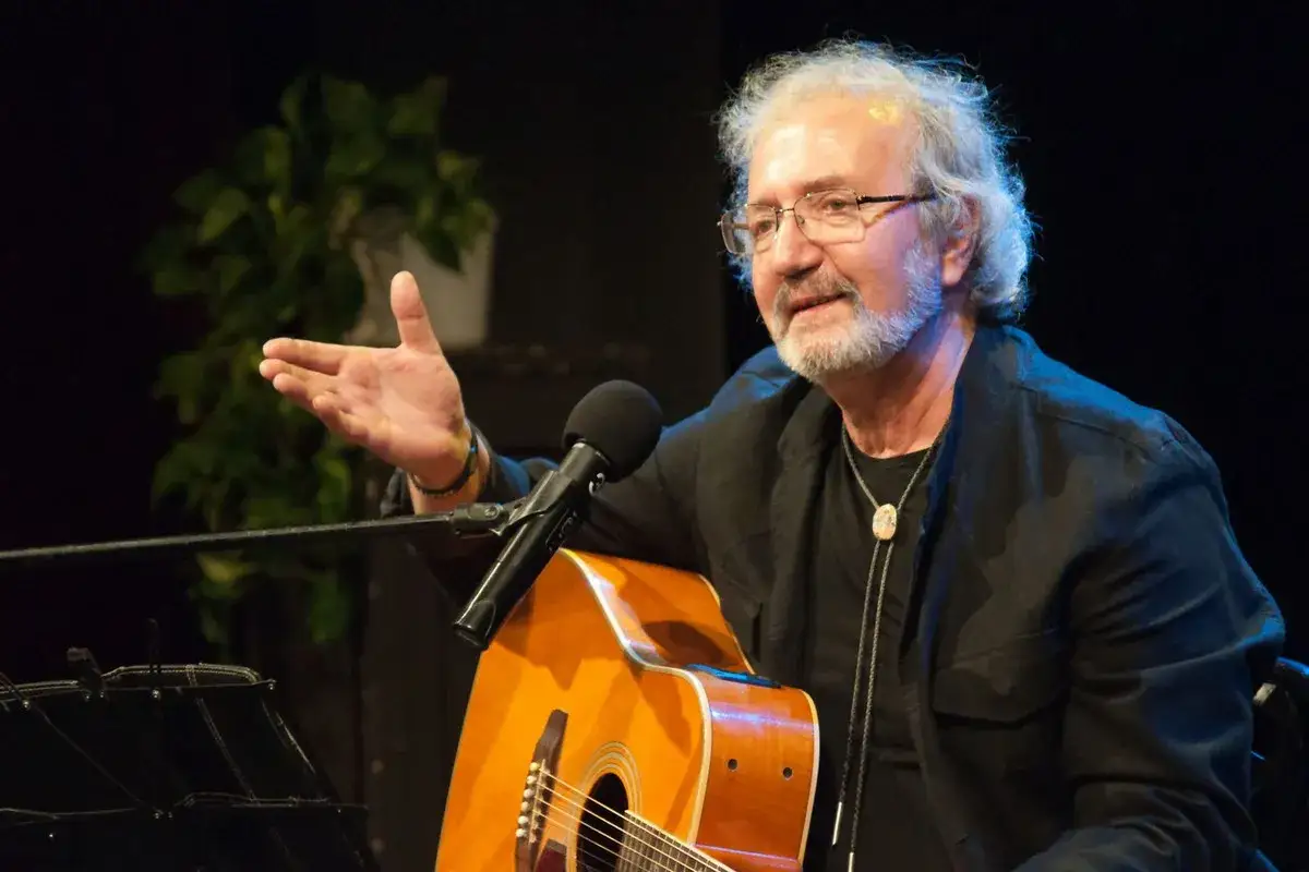 Daukszewicz z gitarą i mikrofonem, gestykuluje podczas występu.