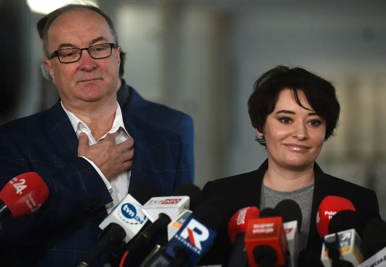 Włodzimierz Czarzasty syn, polityk w okularach, i młoda kobieta z krótkimi włosami, otoczeni przez mikrofony mediów.