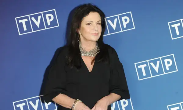 Zofia Czernicka w czarnej kreacji, z okazałą biżuterią, na tle logo TVP. Wiele osób zastanawia się, kim są jej partnerzy.