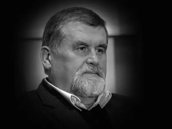 Portret Andrzeja Zielińskiego, mężczyzny z siwą brodą i zmarszczkami, w czarnym garniturze.