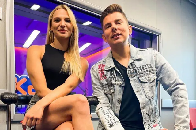Kasia Węsierska i mężczyzna w studiu radiowym. Kasia ma blond włosy i czarną sukienkę. Mężczyzna nosi dżinsową kurtkę z napisami.